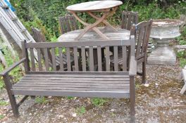 A MODERN HARDWOOD GARDEN TABLE, 120cm in diameter, four similar chairs, a coffee table and a bench