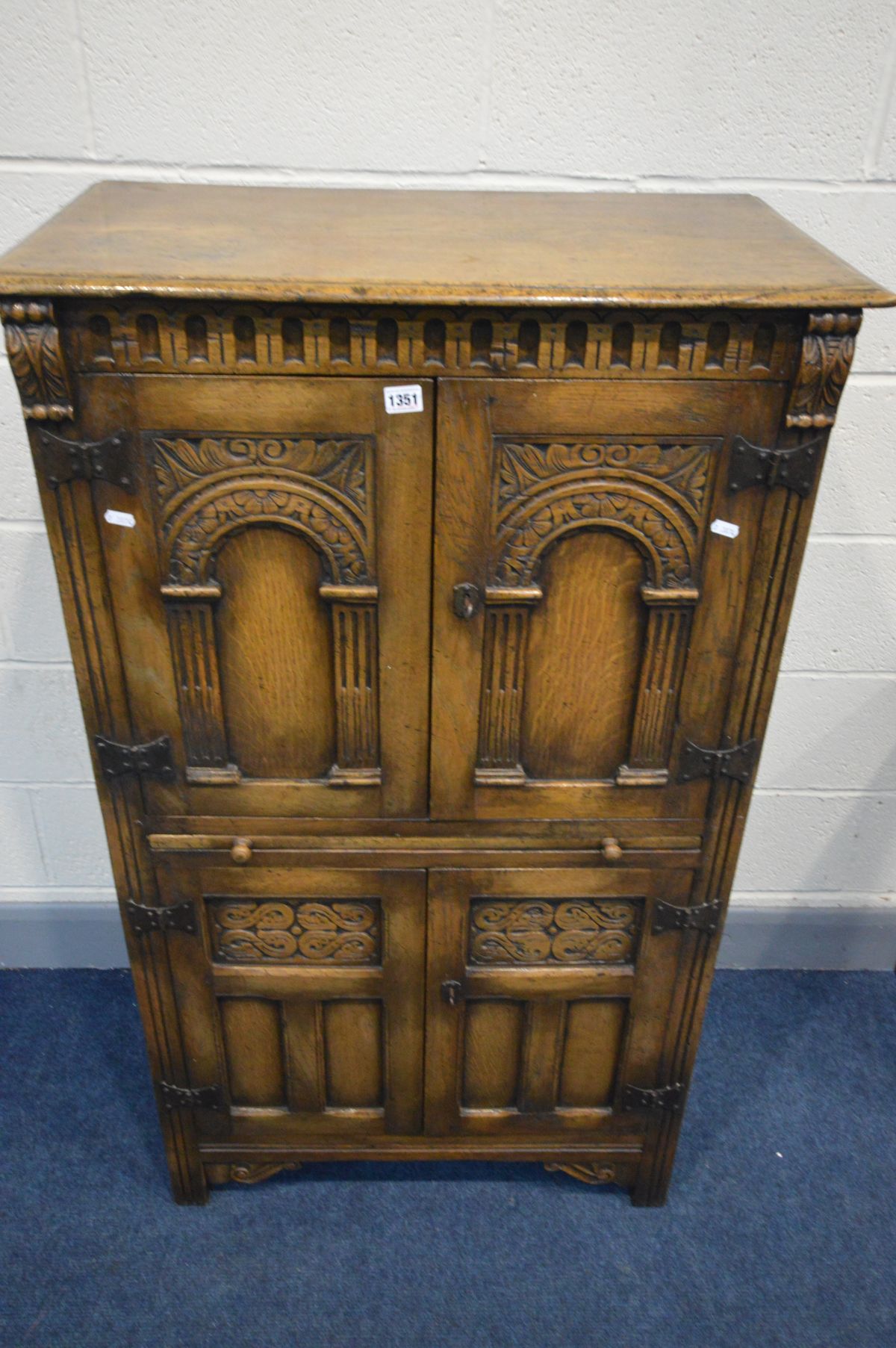 A REPRODUCTION OAK FOUR DOOR DRINKS CABINET, the arched panel door enclosing an arched shelf, and