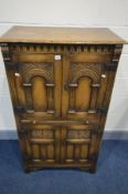 A REPRODUCTION OAK FOUR DOOR DRINKS CABINET, the arched panel door enclosing an arched shelf, and