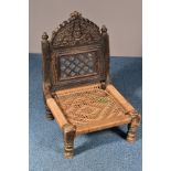 AN ANGLO-INDIAN HARDWOOD SEAT, the folding back with a carved top rail flanked by finials above a