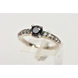 A WHITE METAL CUBIC ZIRCONIA SET DRESS RING, designed with a central, circular cut black stone,