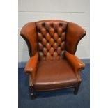 A BURNT ORANGE LEATHER BUTTON WINGBACK ARMCHAIR (condition - rip to left arm, crack to right arm,