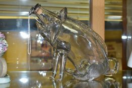 A NOVELTY GLASS DECANTER IN THE OF A SEATED PIG OR GIN PIG, free blown form with cork and metal