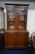 AN EDWARDIAN WALNUT GLAZED TWO DOOR BOOKCASE, enclosing triple adjustable shelves and three drawers,