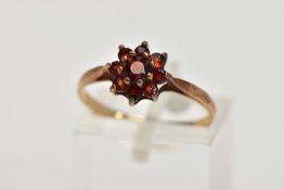 A 9CT GOLD GARNET CLUSTER RING, flower shape cluster set with circular cut garnets, tapered