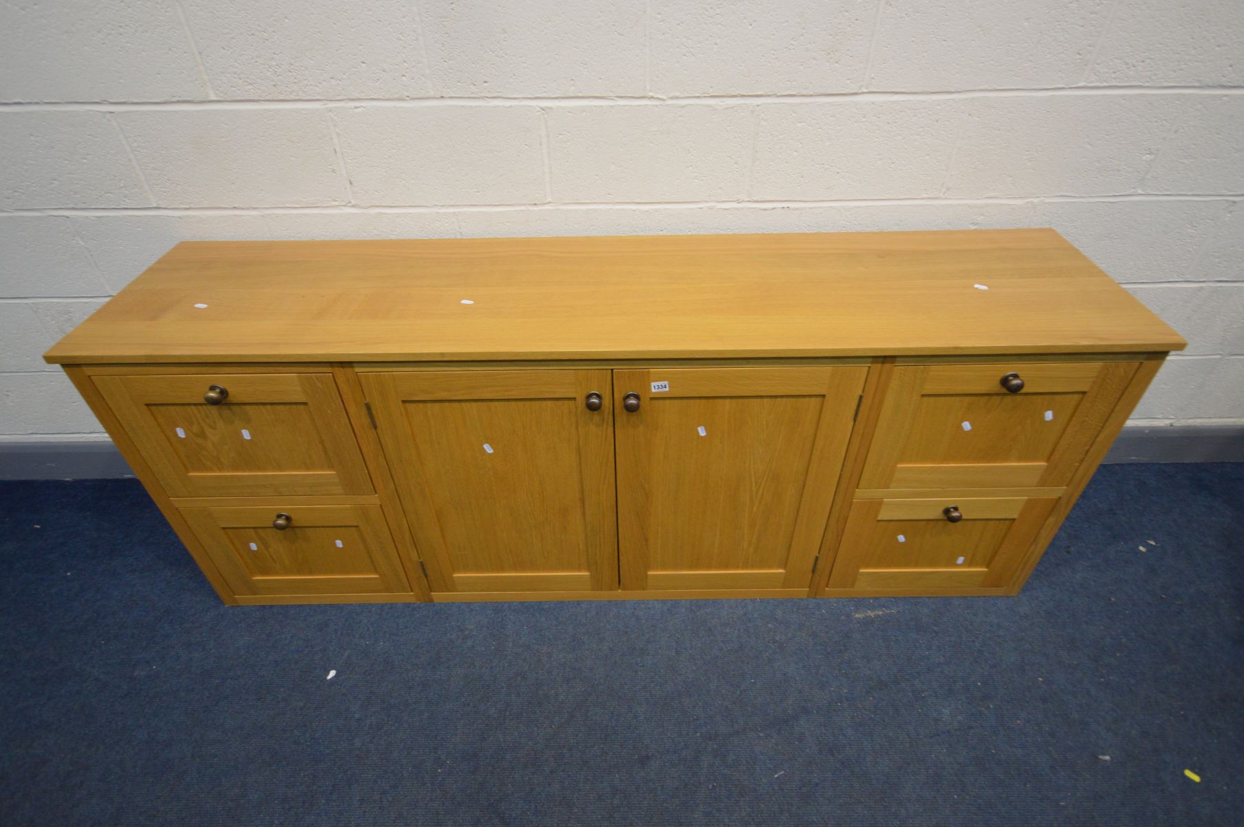 A LIGHT OAK SIDEBOARD with four deep drawers flanking double cupboard doors, width 204cm x depth