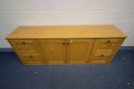 A LIGHT OAK SIDEBOARD with four deep drawers flanking double cupboard doors, width 204cm x depth