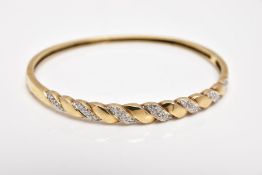 A 9CT GOLD DIAMOND SET HINGED BANGLE, of twist design, set with diagonal sections of single cut