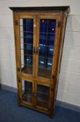 AN OAK LEAD GLAZED FOUR DOOR DISPLAY CABINET, enclosing five glass shelves and smoked mirror back,