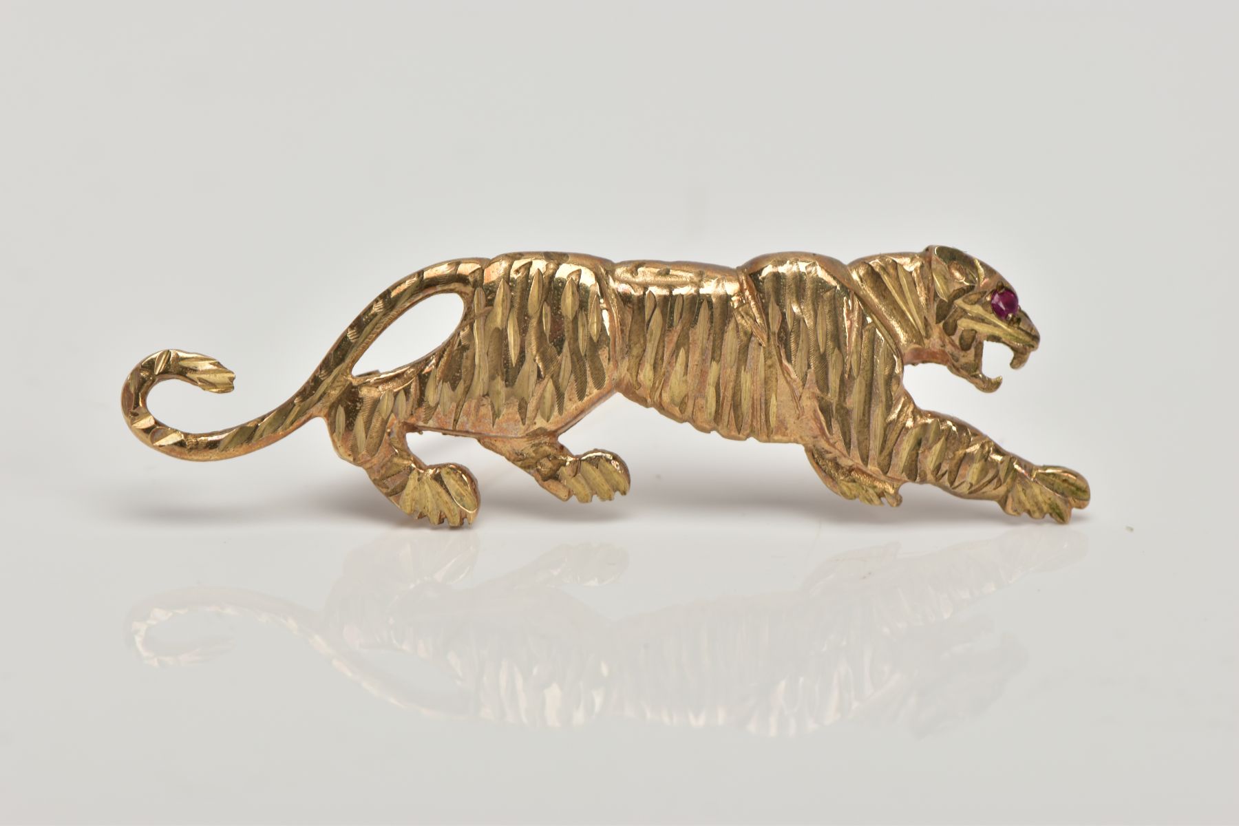 A 9CT GOLD BROOCH, in the form of a realistically stylised tiger, set with a circular cut ruby