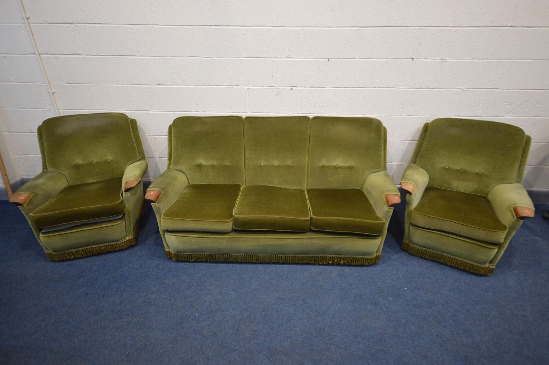 A 1960S GREEN UPHOLSTERED FOUR PIECE LOUNGE SUITE, teak outswept armrests, comprising a settee,