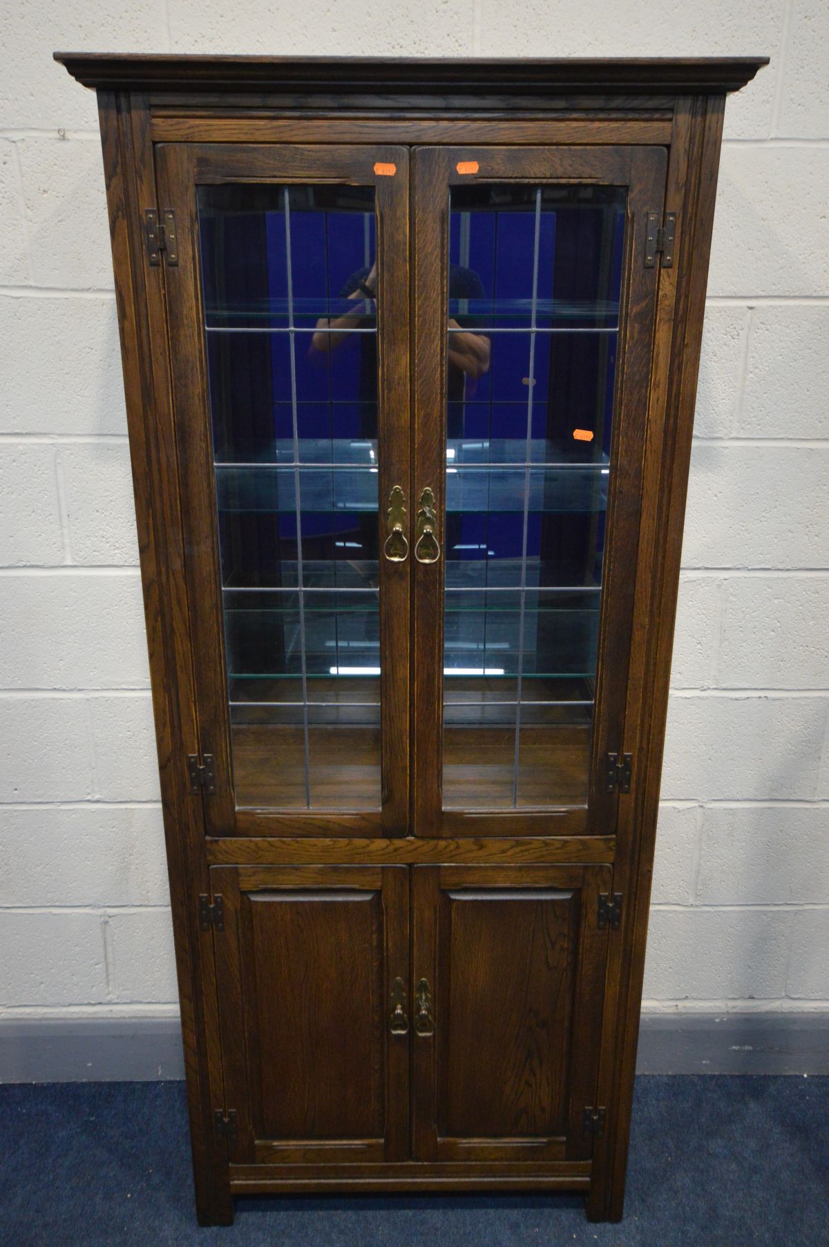 AN OAK LEAD GLAZED TWO DOOR DISPLAY CABINET, enclosing three glass shelves and smoked mirror back,