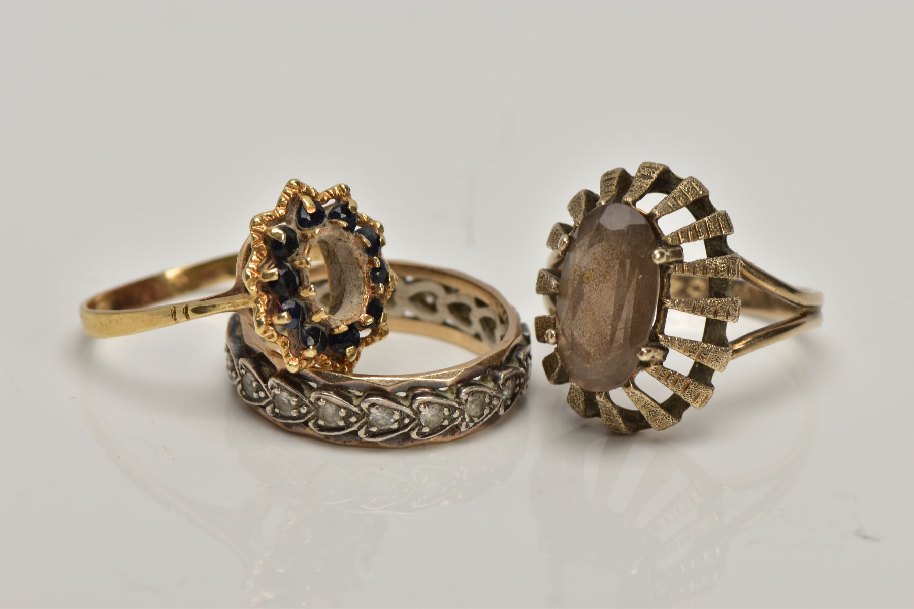 A 9CT GOLD DRESS RING AND TWO YELLOW METAL RINGS, the first of an oval shape set with an oval cut