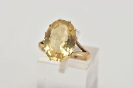 A YELLOW METAL CITRINE DRESS RING, designed with a claw set oval cut citrine, openwork gallery,