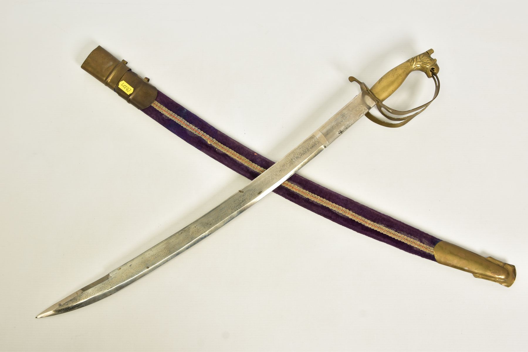 AN INDIAN MADE CURVED SWORD, in a wooden scabbard trimmed with purple coloured velvet style cloth