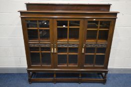 A MAHOGANY GLAZED BOOKCASE, with a raised back, triple doors enclosing three adjustable shelves to