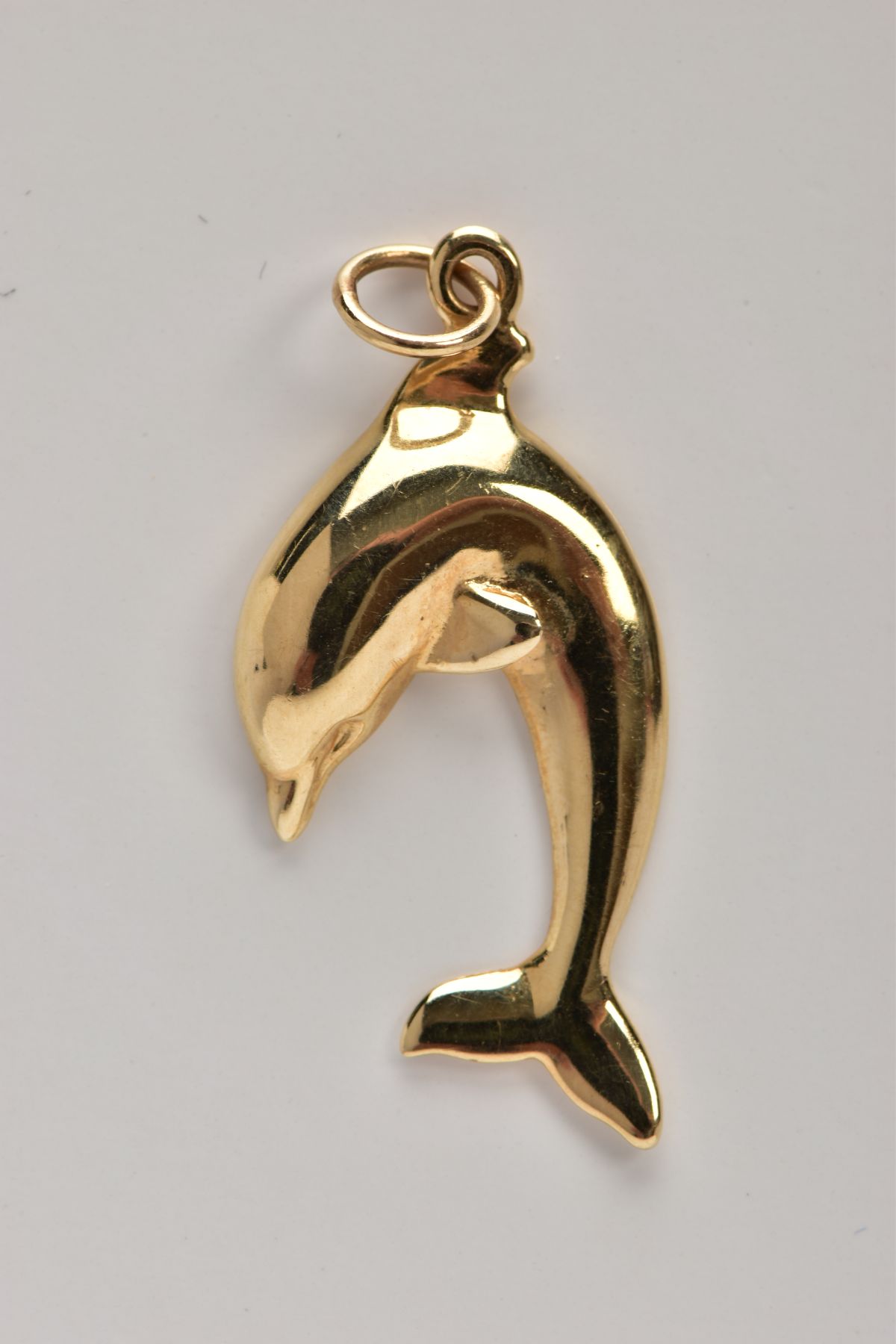 A YELLOW METAL DOLPHIN PENDANT, fitted with a suspension ring, stamped to the reverse '14k',