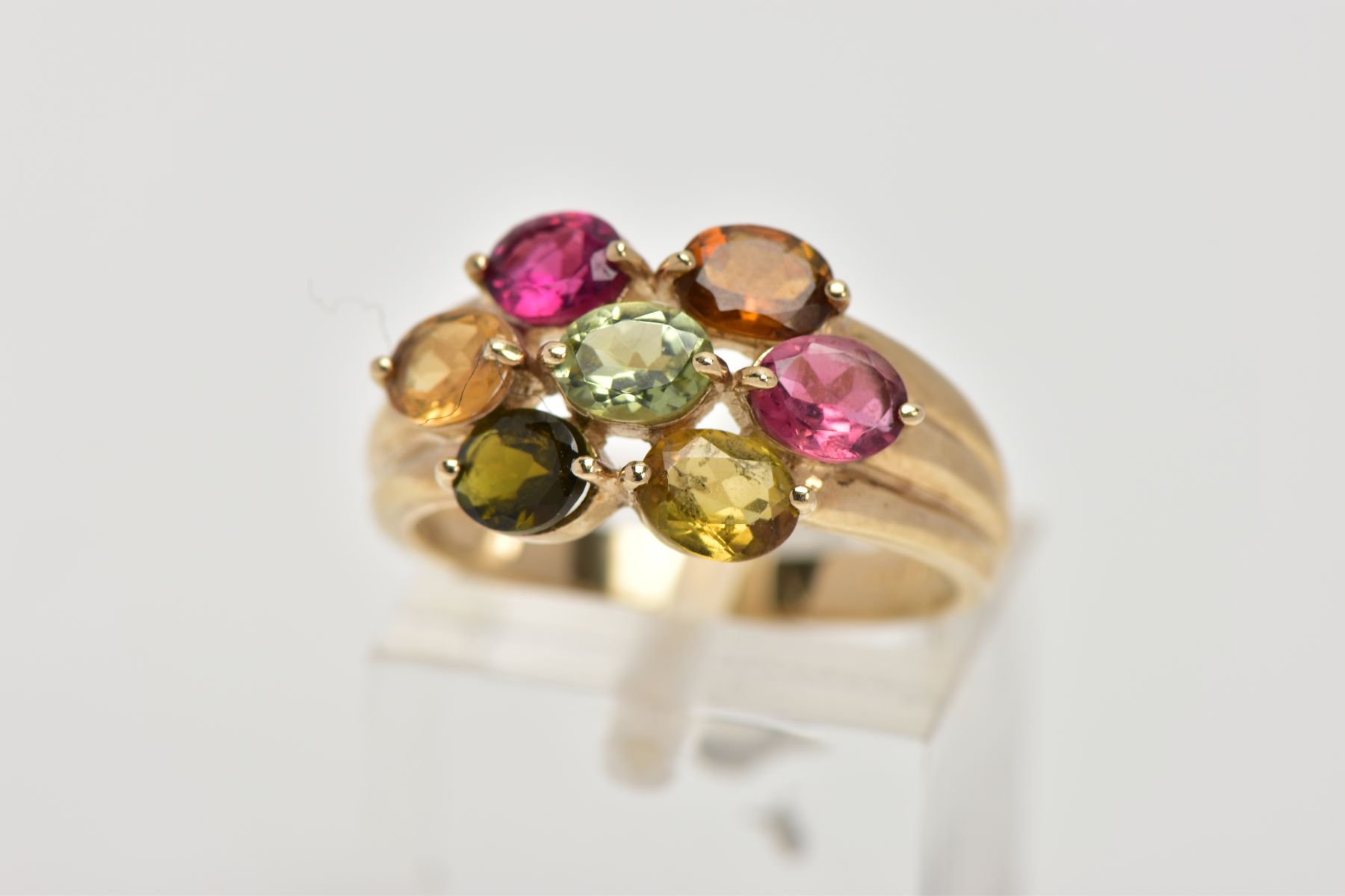 A 9CT GOLD GEM SET RING, of a cluster form, set with seven oval cut, differing colour gemstones