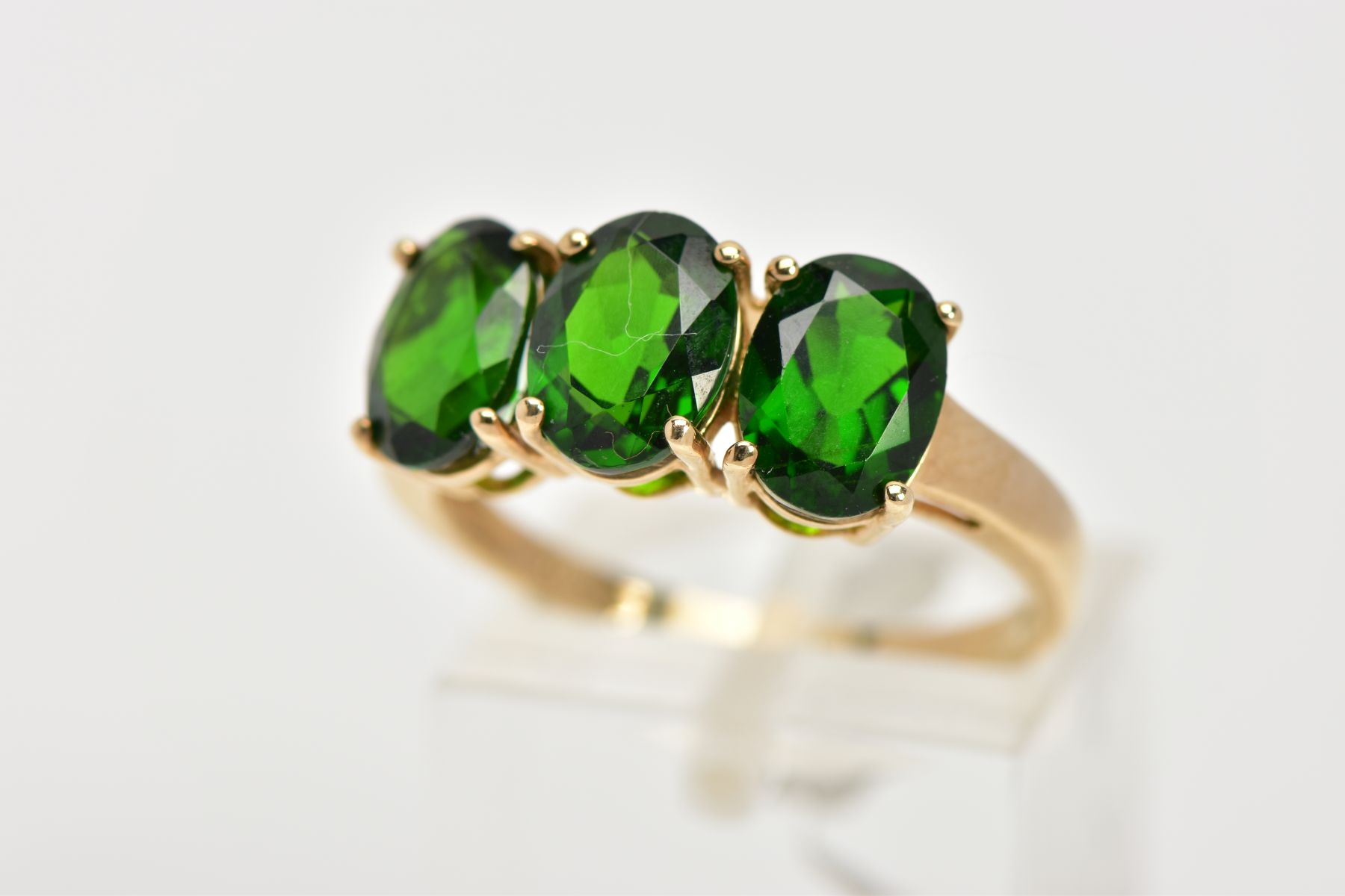 A 9CT GOLD THREE STONE TOURMALINE DRESS RING, designed with three oval cut, green stones assessed as