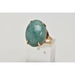 A YELLOW METAL DRESS RING, designed with a claw set, oval green stone assessed as jade, openwork