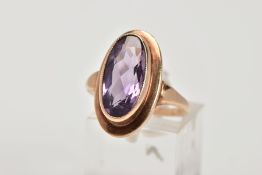 A 9CT GOLD AMETHYST DRESS RING, designed with an oval cut amethyst within a collet mount,