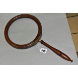 AN OVERSIZED WALNUT FRAMED MAGNIFYING GLASS, moulded circular frame, brass mount with turned screw