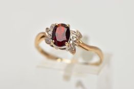 A 9CT GOLD GARNET AND DIAMOND CLUSTER RING, designed with a central oval cut garnet, flanked with