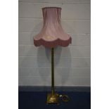 A BRASS BARLEY TWIST STANDARD LAMP on a stepped base, with claw feet, with a pink fabric shade,