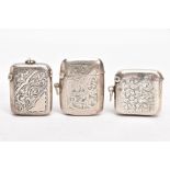THREE EARLY 20TH CENTURY SILVER VESTAS, each with an engraved foliate design, one with engraved