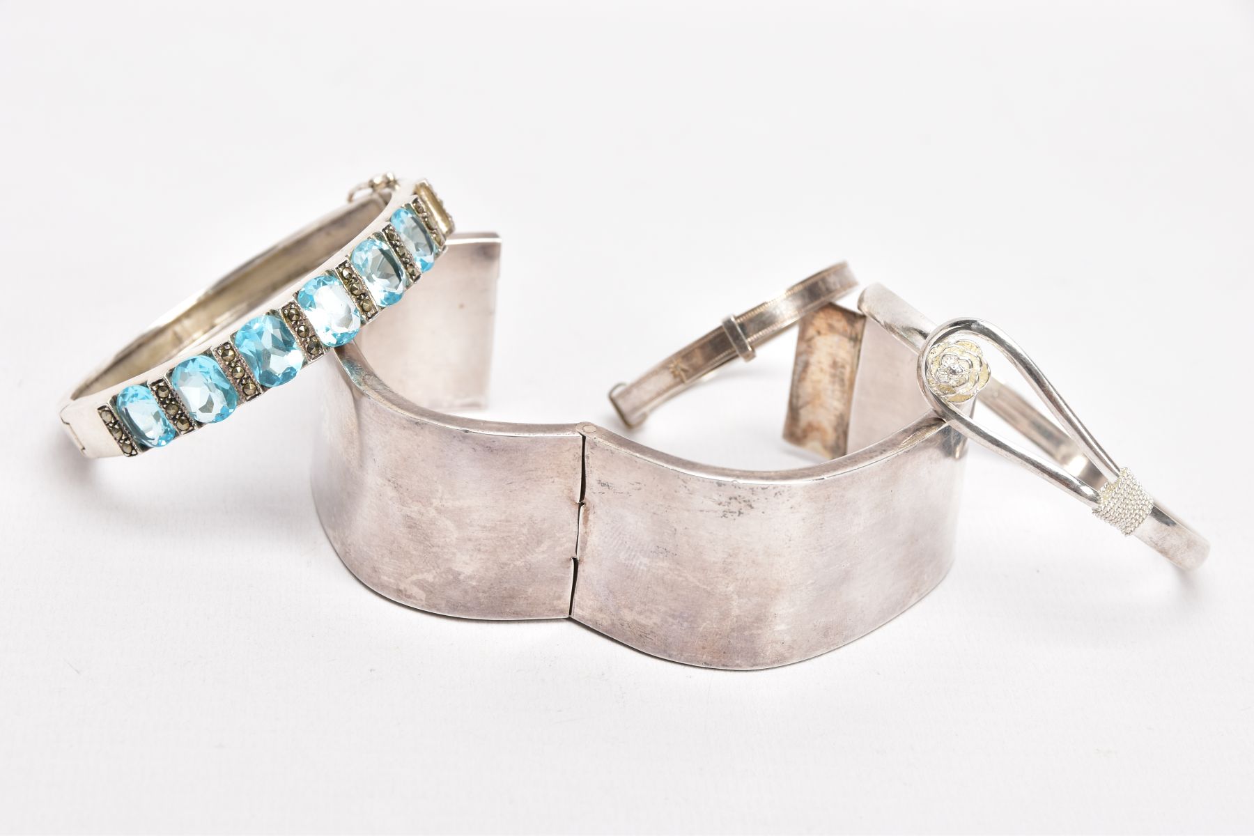 FOUR WHITE METAL BANGLES, the first a plain polished square shaped bangle, fitted with a push pin