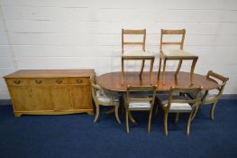 A YEW WOOD DINING SUITE comprising a twin pedestal dining table with additional leaf, six matching