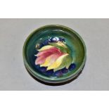A SMALL MOORCROFT POTTERY FOOTED BOWL, leaf and berry pattern on a green ground, impressed and