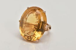 A LARGE CITRINE DRESS RING, yellow metal ring, six claw set, oval cut citrine, measuring