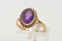 A 9CT GOLD AMETHYST DRESS RING, designed with an oval cut amethyst, collet mount within a rope twist