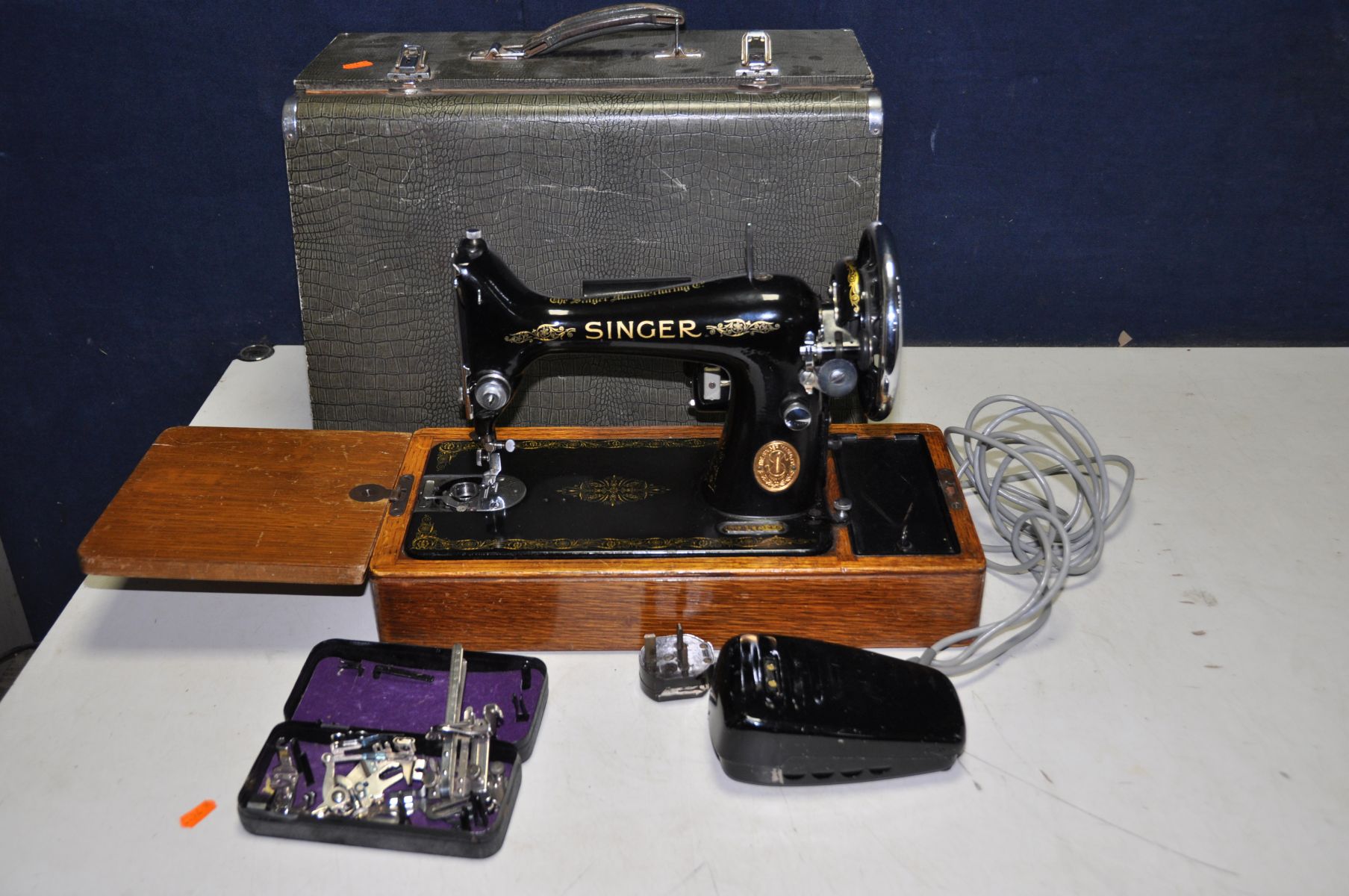 A VINTAGE CASED ELECTRIC SINGER SEWING MACHINE with green Alligator skin style case, a tin of