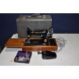 A VINTAGE CASED ELECTRIC SINGER SEWING MACHINE with green Alligator skin style case, a tin of