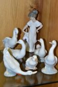 A NAO FIGURE OF A GIRL IN A CREAM DRESS AND SIX NAO DUCK FIGURES IN VARIOUS POSES, the girl height