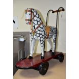 A CHILDS PUSH ALONG WOODEN HORSE, black and white dapple horse on maroon board with black wheels,