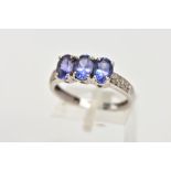 A 9CT WHITE GOLD, TANZANITE AND DIAMOND DRESS RING, designed with three, four claw set, oval cut