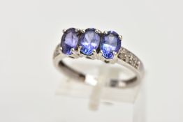 A 9CT WHITE GOLD, TANZANITE AND DIAMOND DRESS RING, designed with three, four claw set, oval cut