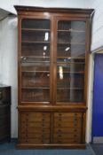 AN IMPRESSIVELY TALL VICTORIAN WALNUT BOOKCASE, the overhanging cornice on two large glazed doors,