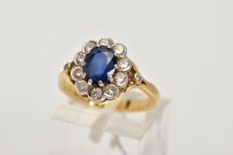 AN 18CT GOLD SAPPHIRE AND DIAMOND CLUSTER RING, centring on an oval cut blue sapphire, within a