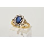 AN 18CT GOLD SAPPHIRE AND DIAMOND CLUSTER RING, centring on an oval cut blue sapphire, within a