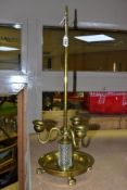 A BRASS AND GLASS THREE BRANCH CANDLE HOLDER, fitted with a central carrying handle to a three