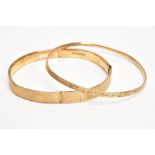 A 9CT GOLD BANGLE AND A YELLOW METAL BANGLE, the first an AF bangle of an engine turned design, (