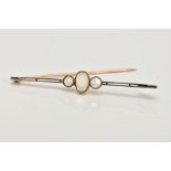 AN EARLY 20TH CENTURY MOONSTONE BAR BROOCH, set with a central oval moonstone cabochon, flanked by