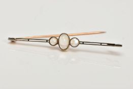 AN EARLY 20TH CENTURY MOONSTONE BAR BROOCH, set with a central oval moonstone cabochon, flanked by