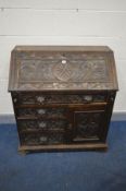 A LATE 19TH/EARLY 20TH CENTURY CARVED OAK BUREAU, with foliate detail and mask handles, width 92cm x