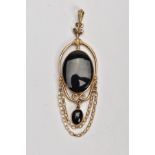 A 9CT GOLD ONYX PENDANT, the oval collet set onyx within a scrolling wire surround suspending a
