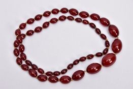 A GRADUATED CHERRY AMBER COLOUR BEADED NECKLACE, fifty-two graduated oval beads, individually